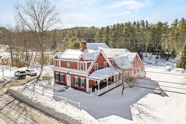 snowy aerial view with a wooded view