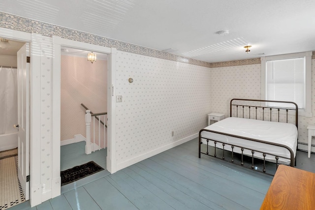 bedroom featuring wallpapered walls, baseboards, wood finished floors, and a baseboard heating unit