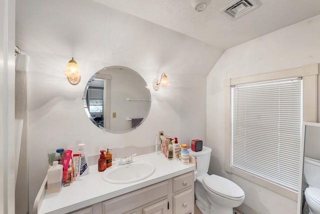 bathroom featuring toilet, lofted ceiling, visible vents, and vanity