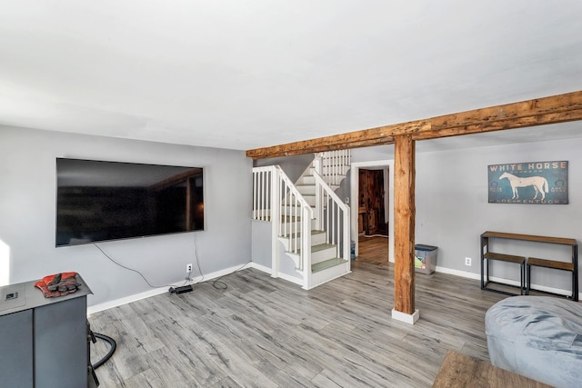 living room with stairs, baseboards, wood finished floors, and beamed ceiling