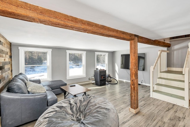 living area with baseboards, stairs, beam ceiling, light wood finished floors, and a wood stove