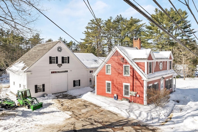 snow covered property featuring a garage and a chimney