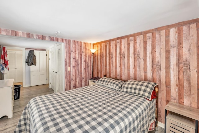 bedroom with wood walls and wood finished floors