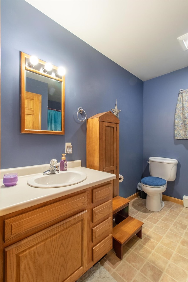 bathroom with toilet, baseboards, and vanity