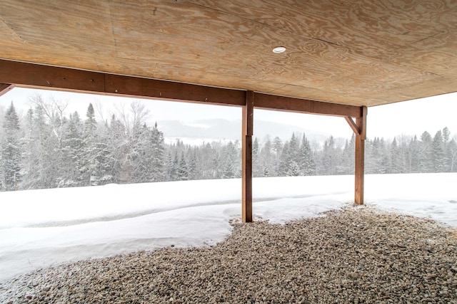 yard layered in snow featuring a wooded view