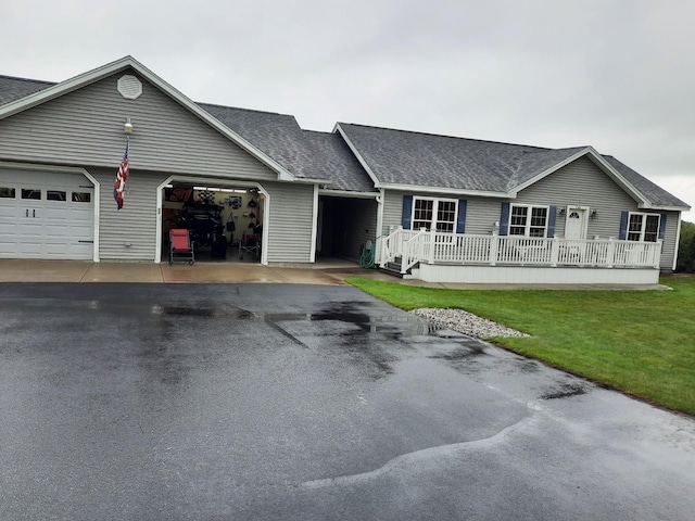 single story home featuring driveway, an attached garage, a front lawn, and a shingled roof