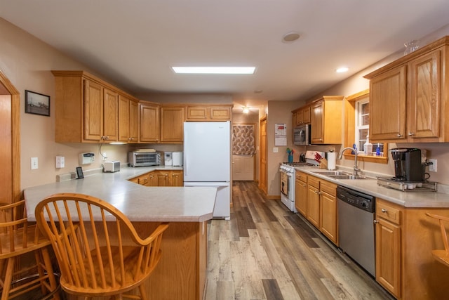 kitchen featuring light countertops, appliances with stainless steel finishes, a sink, and light wood-style flooring