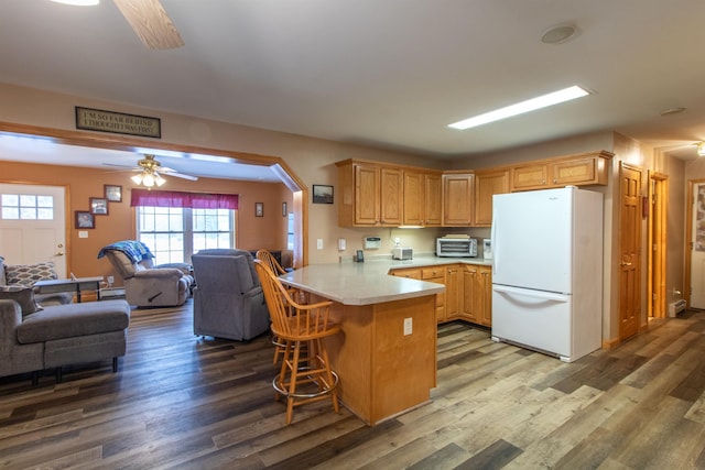 kitchen with arched walkways, a peninsula, open floor plan, light countertops, and freestanding refrigerator