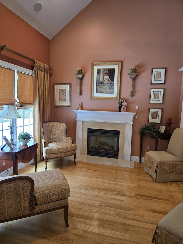 sitting room with vaulted ceiling, a tiled fireplace, and wood finished floors