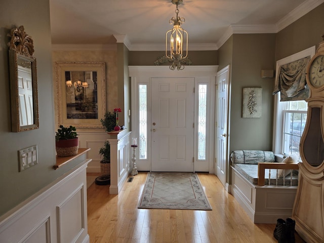 foyer entrance with a wainscoted wall, a decorative wall, light wood-style flooring, and crown molding