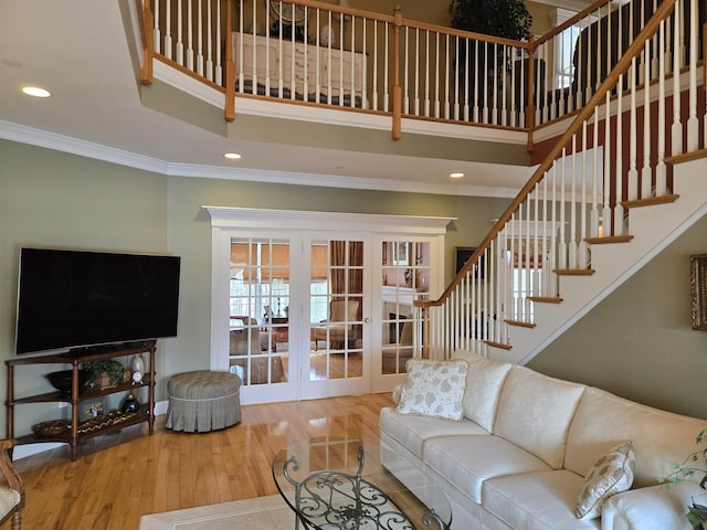 living room featuring french doors, crown molding, wood-type flooring, stairway, and a towering ceiling