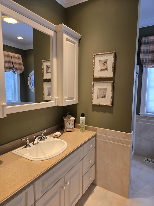 bathroom with visible vents, wainscoting, tile patterned flooring, vanity, and tile walls