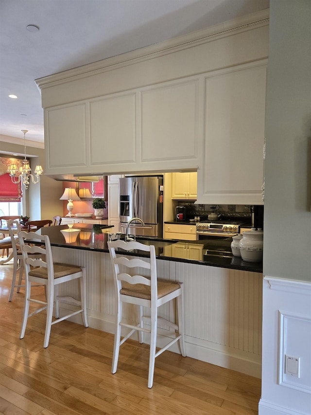 kitchen featuring dark countertops, a peninsula, light wood-style floors, a kitchen bar, and stainless steel refrigerator with ice dispenser