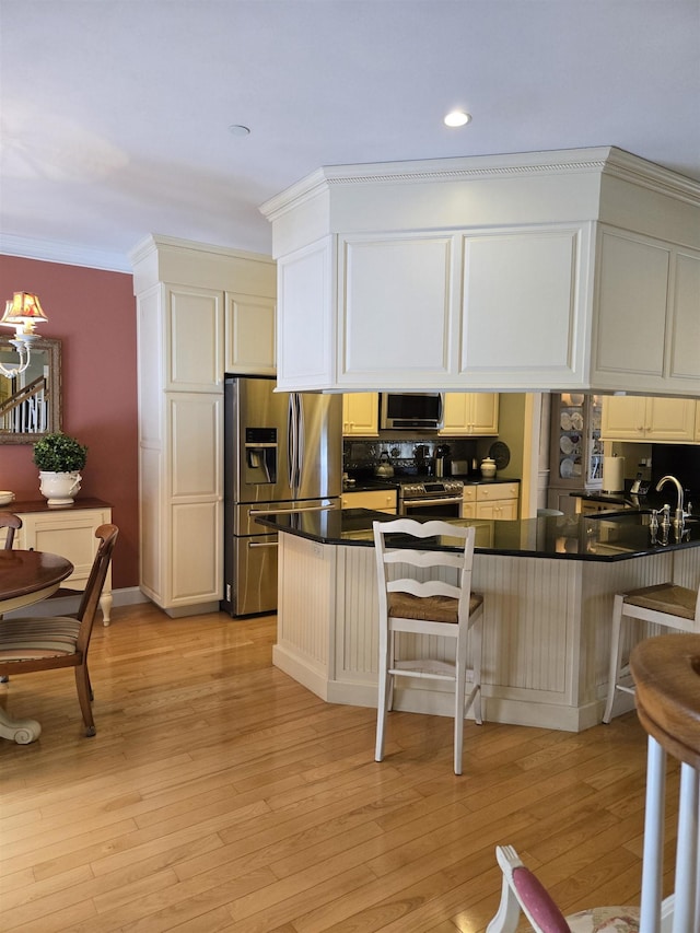 kitchen featuring ornamental molding, appliances with stainless steel finishes, a breakfast bar area, and dark countertops