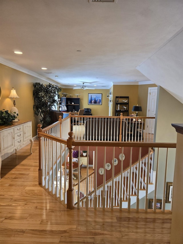 hallway with visible vents, crown molding, an upstairs landing, and wood finished floors