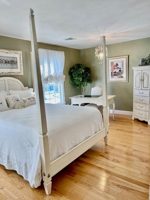 bedroom featuring baseboards, a chandelier, visible vents, and light wood-style floors