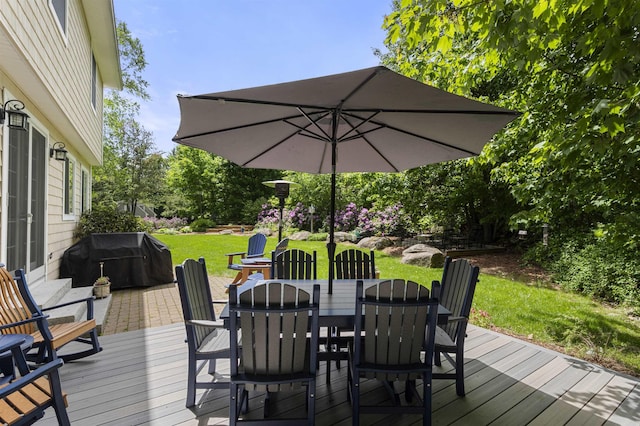 deck with grilling area, outdoor dining area, and a lawn