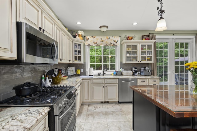 kitchen with appliances with stainless steel finishes, plenty of natural light, backsplash, and cream cabinetry