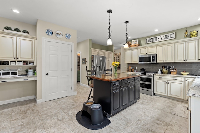 kitchen with appliances with stainless steel finishes, cream cabinets, backsplash, and a kitchen bar