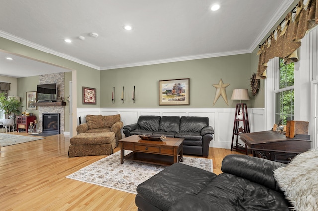 living area featuring wainscoting, ornamental molding, a fireplace, and wood finished floors