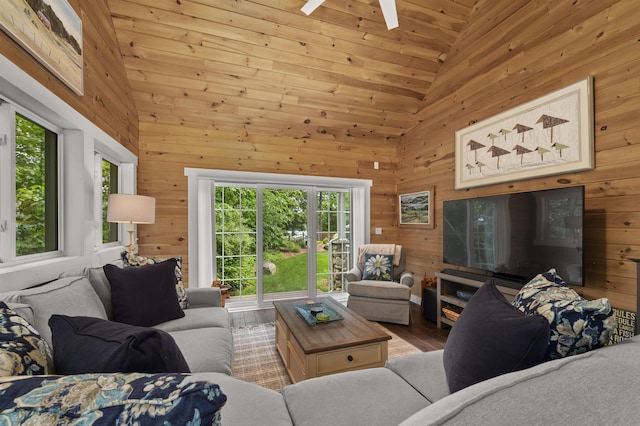 living room featuring wooden walls, high vaulted ceiling, and wood finished floors