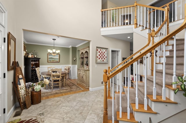 tiled entryway with a chandelier, stairway, crown molding, and a towering ceiling