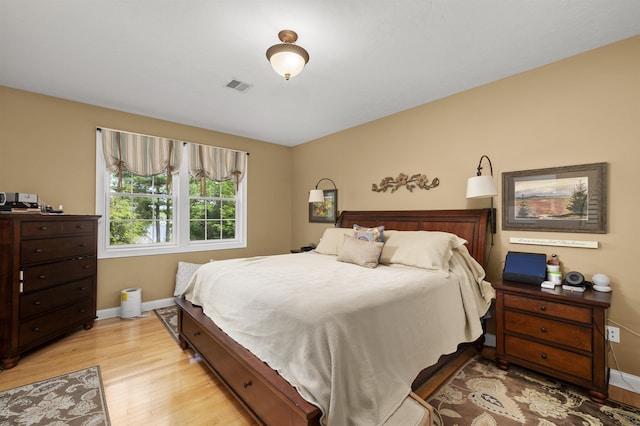 bedroom featuring light wood-style flooring, visible vents, and baseboards