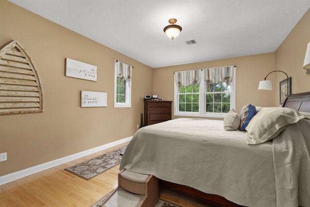 bedroom featuring visible vents, baseboards, and wood finished floors