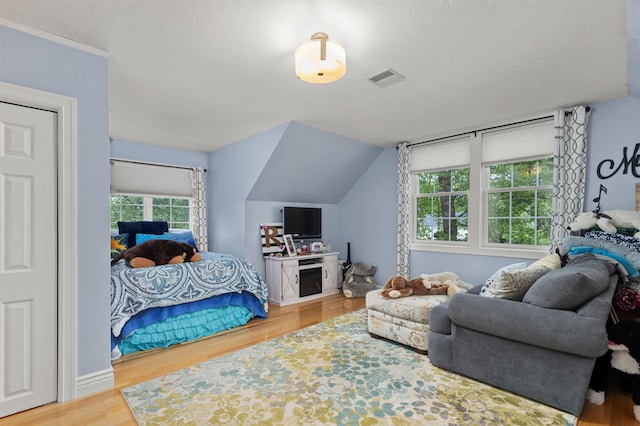 bedroom featuring lofted ceiling, visible vents, and wood finished floors