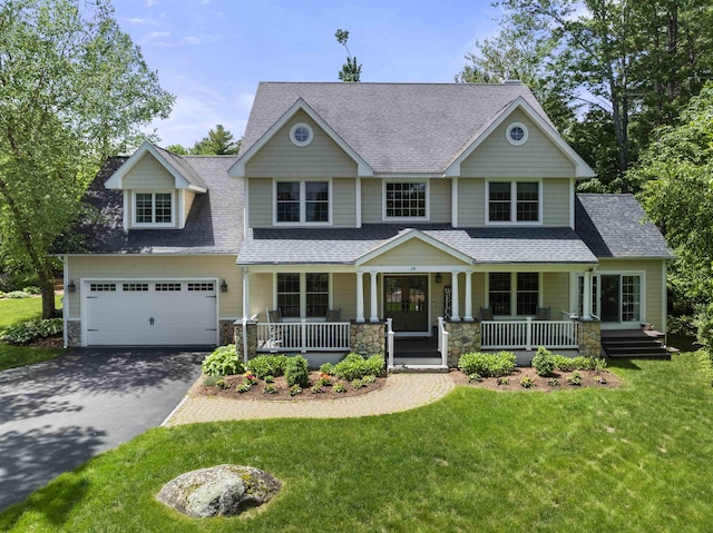 craftsman inspired home with covered porch, aphalt driveway, a front lawn, and a shingled roof