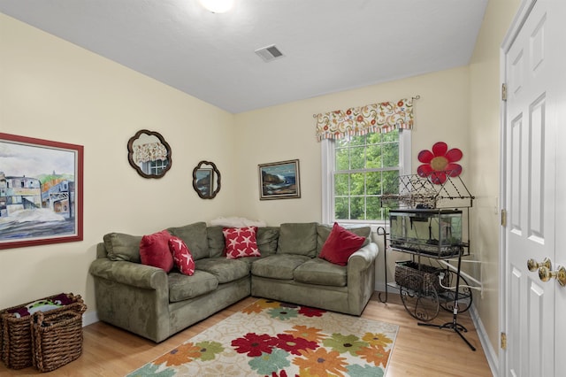 living room with light wood-style flooring, visible vents, and baseboards