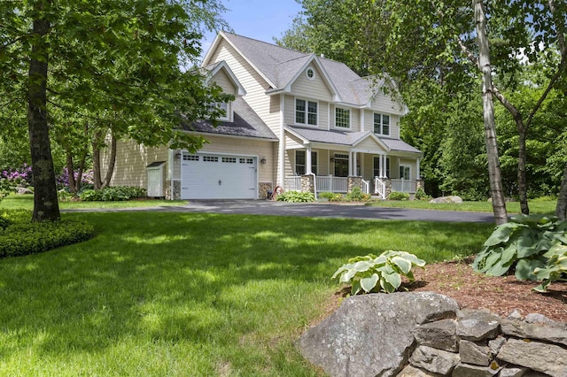 view of front of property featuring a porch, a shingled roof, an attached garage, driveway, and a front lawn