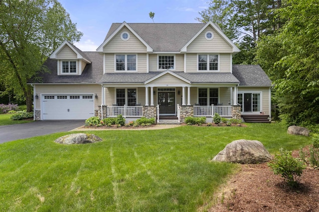 craftsman-style home with stone siding, aphalt driveway, covered porch, and a front yard