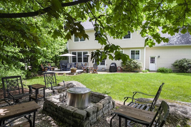 back of property with an outdoor fire pit, a patio, and a lawn