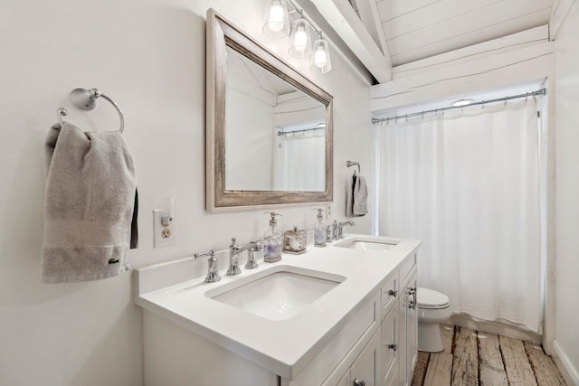 full bath with toilet, double vanity, a sink, and wood finished floors