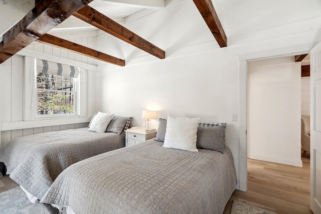 bedroom with lofted ceiling with beams and wood finished floors