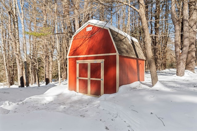 snow covered structure featuring an outdoor structure and a shed