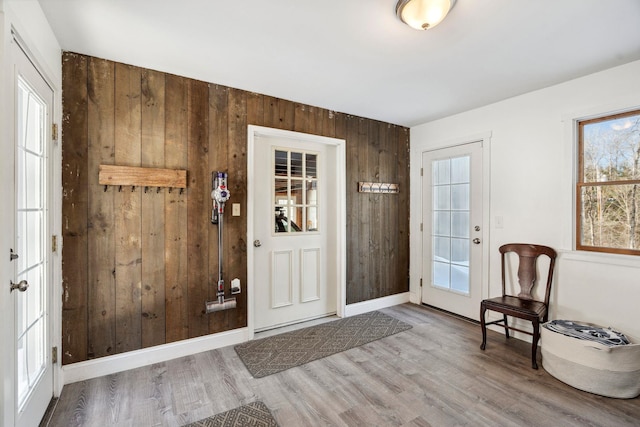 foyer entrance with wood walls, baseboards, and wood finished floors