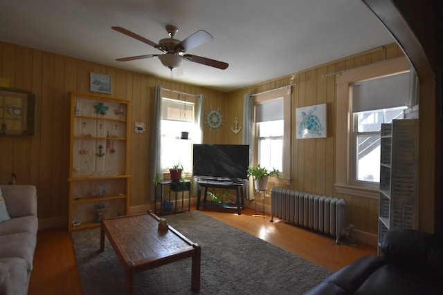 living area featuring arched walkways, radiator heating unit, wood finished floors, and a ceiling fan