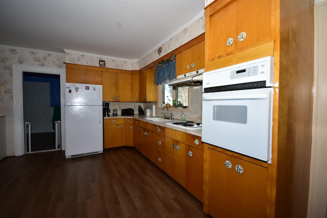 kitchen featuring under cabinet range hood, white appliances, a sink, light countertops, and wallpapered walls