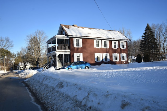 snow covered back of property with a balcony