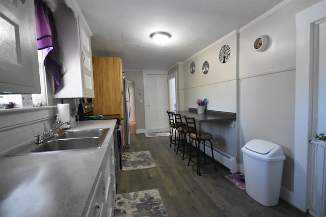 kitchen featuring arched walkways, dark wood-style flooring, baseboard heating, ornamental molding, and white cabinetry