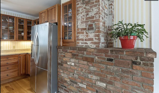 kitchen featuring glass insert cabinets, brown cabinets, and stainless steel refrigerator with ice dispenser