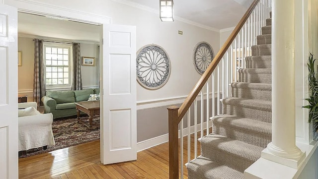 stairs with ornamental molding, ornate columns, a wainscoted wall, and hardwood / wood-style floors