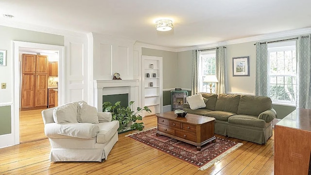 living room featuring light wood finished floors, built in shelves, ornamental molding, and a fireplace