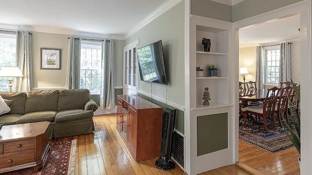 living area with built in features, light wood-type flooring, and crown molding