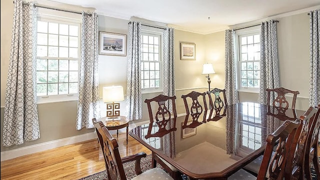 dining space with baseboards, crown molding, and wood finished floors