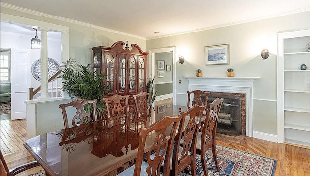 dining space featuring ornamental molding, a fireplace, wood finished floors, and baseboards