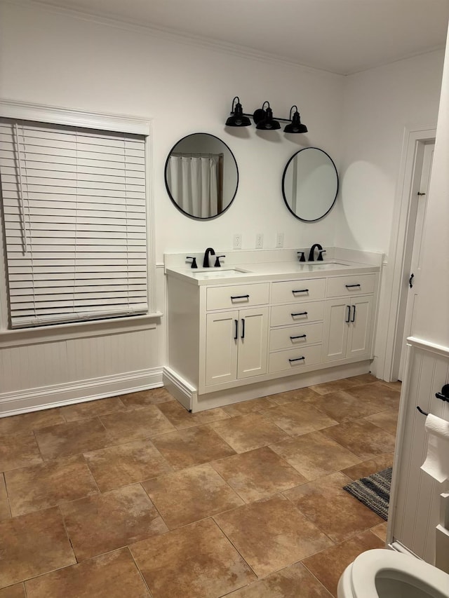 full bath featuring crown molding, a sink, and double vanity