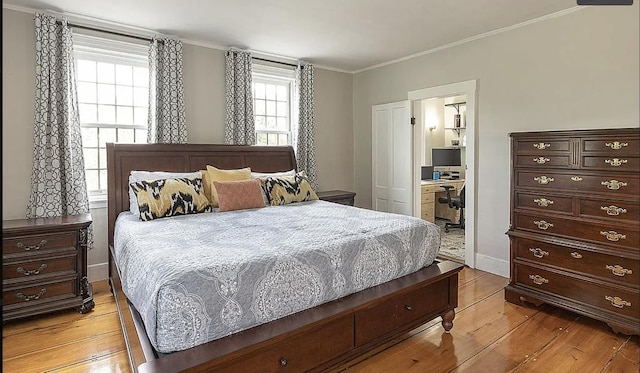 bedroom featuring light wood-style flooring, connected bathroom, baseboards, and crown molding